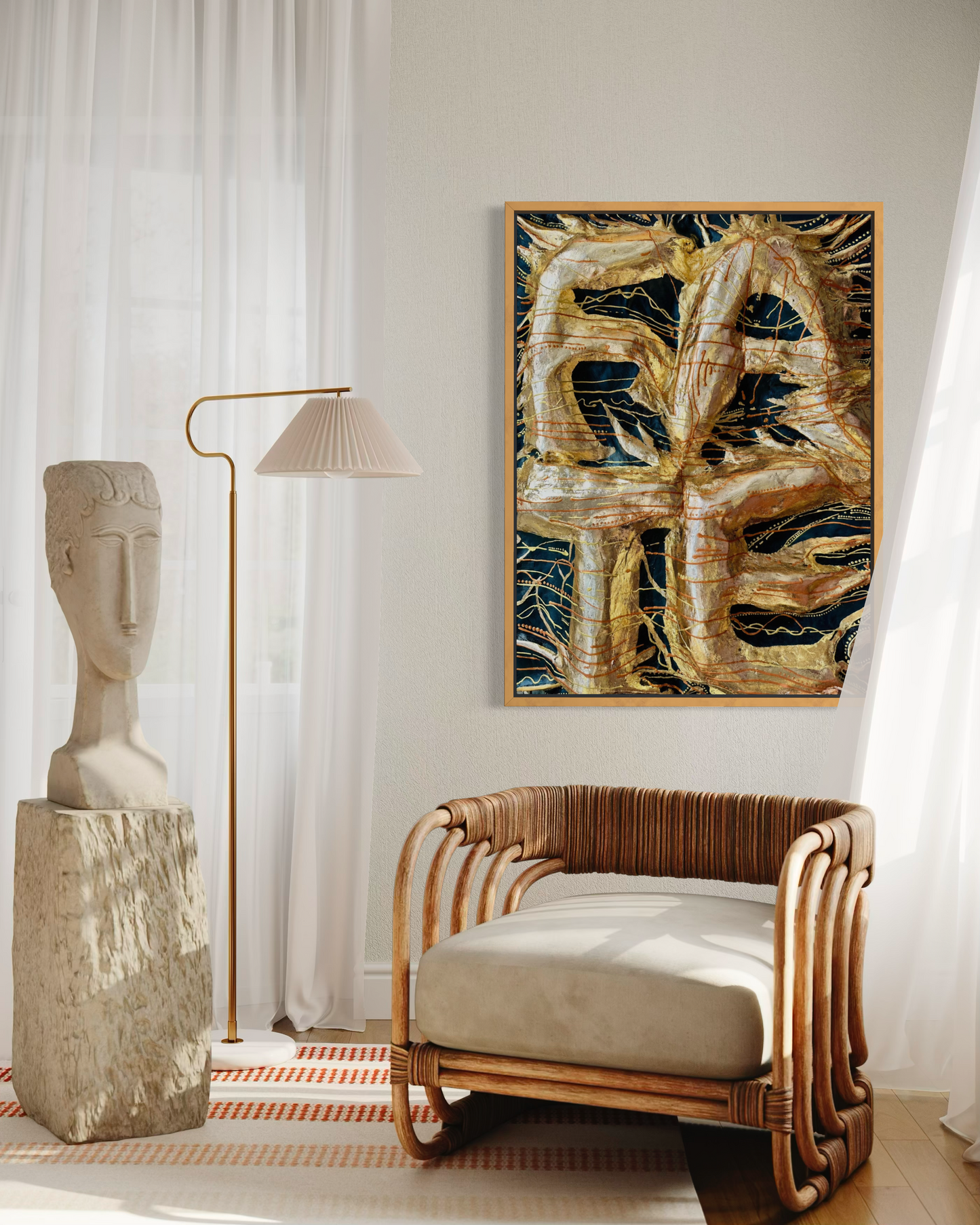 A framed abstract painting with textured gold, brown, and black brushstrokes hangs on a light gray wall in a styled room. The scene includes a rattan armchair with a cream cushion, a floor lamp, a stone bust sculpture, and sheer white curtains.