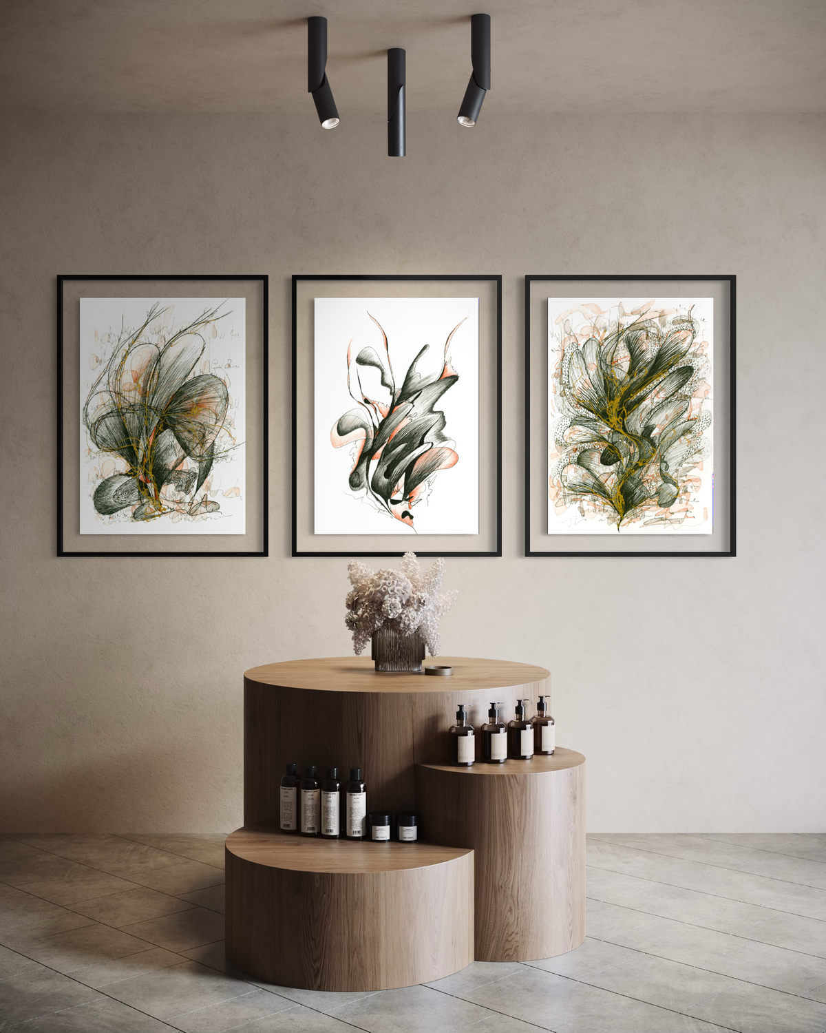 Three framed botanical art prints hang on a beige wall above a wooden display table in a styled interior setting.
