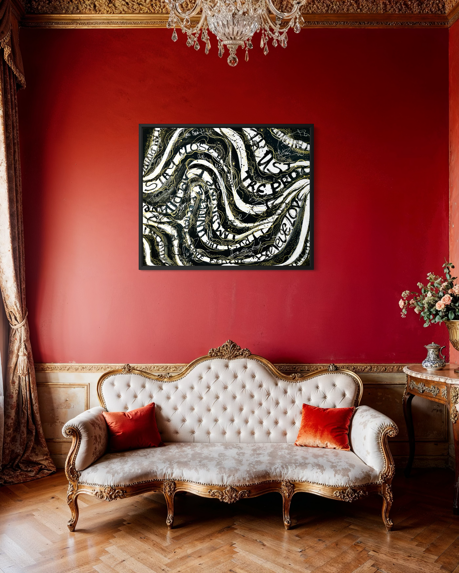 A framed abstract canvas print with black, white, and gray wavy patterns hangs on a deep red wall above an ornate cream and gold sofa in a richly decorated room.