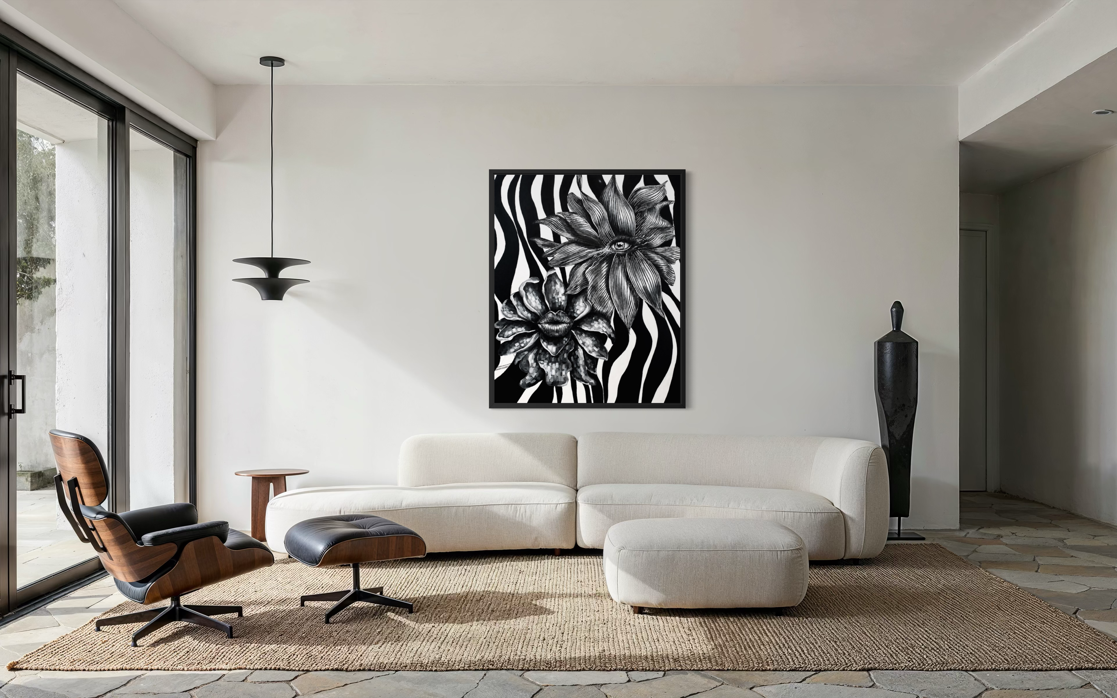 A black and white framed wall art print featuring bold floral and zebra-stripe patterns, displayed in a modern living room setting above a cream-colored sectional sofa.