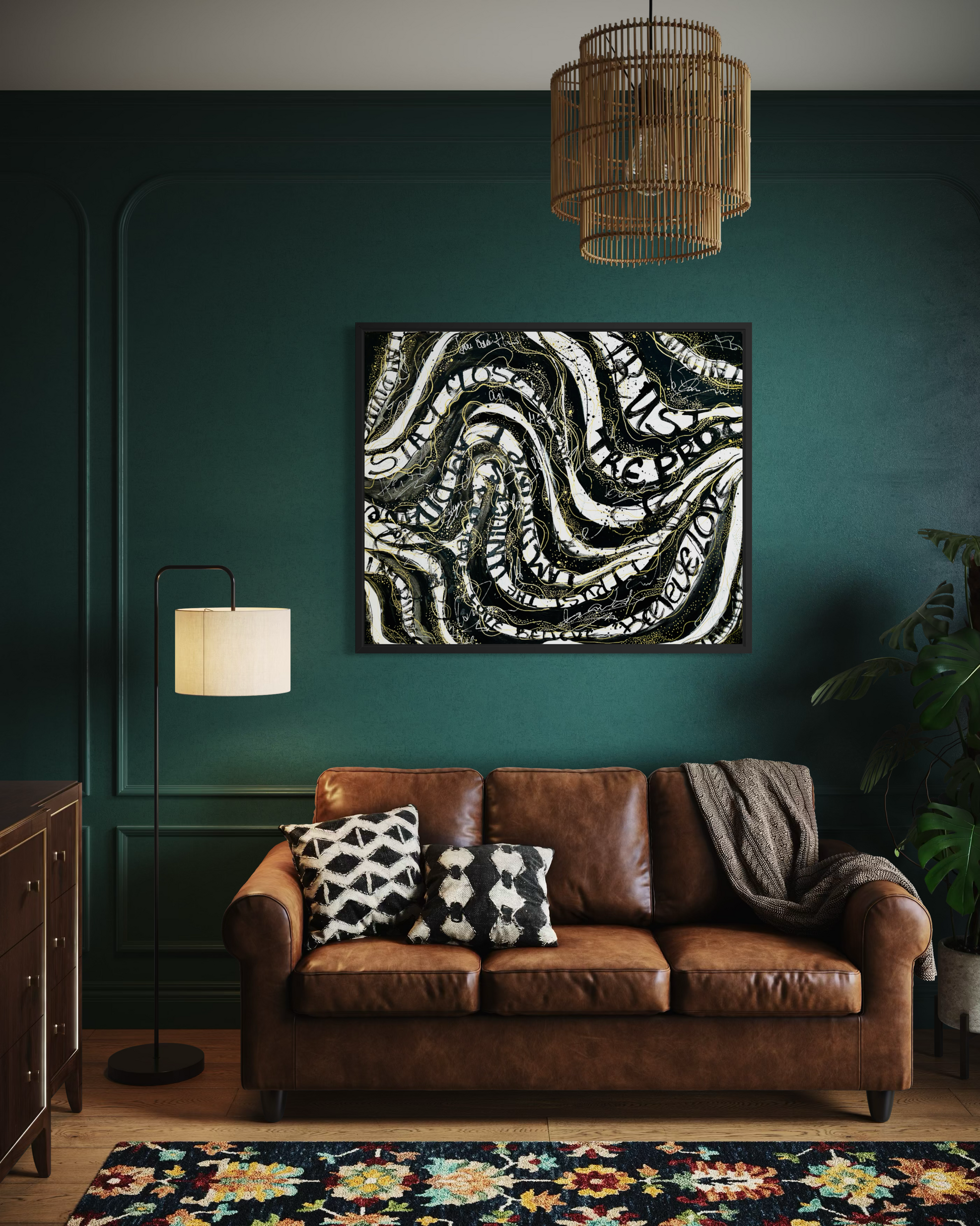 A square abstract canvas print with black, white, and gray swirling patterns, displayed on a dark teal wall above a brown leather sofa in a styled living room.