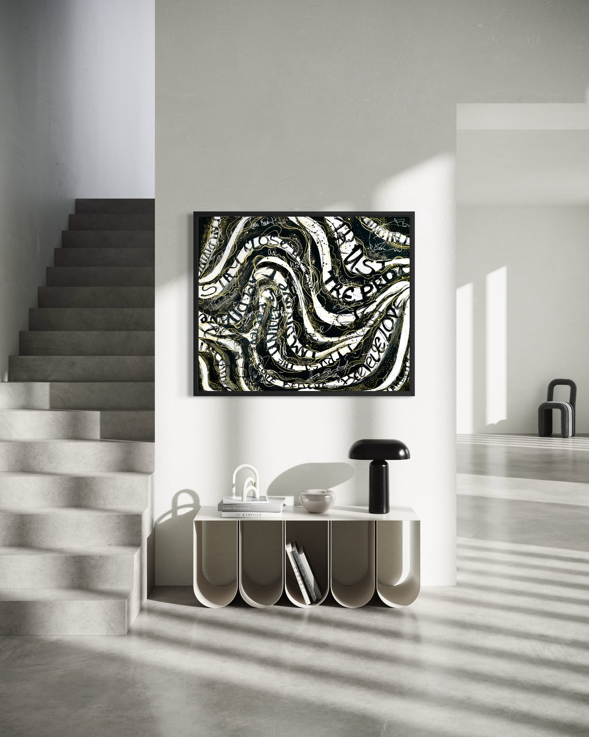 Abstract black and white wavy pattern canvas art hanging on a white wall in a modern minimalist interior with a staircase and console table.