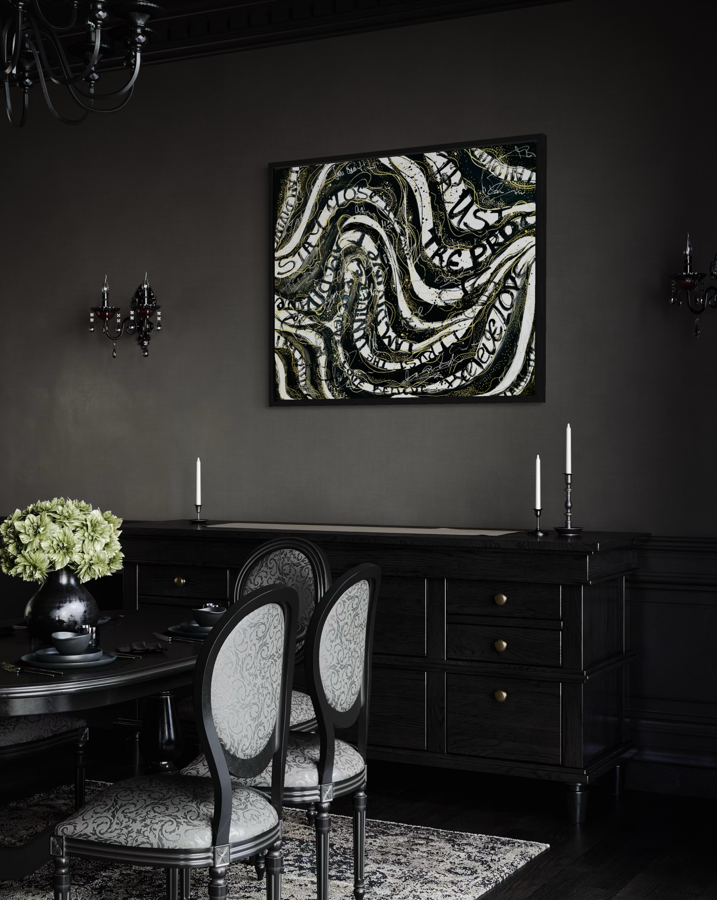 A dark, elegant dining room featuring a large square wall art print with black and white abstract swirling patterns and text. The room has dark gray walls, a black wooden sideboard with candles, patterned dining chairs, and a dark chandelier.