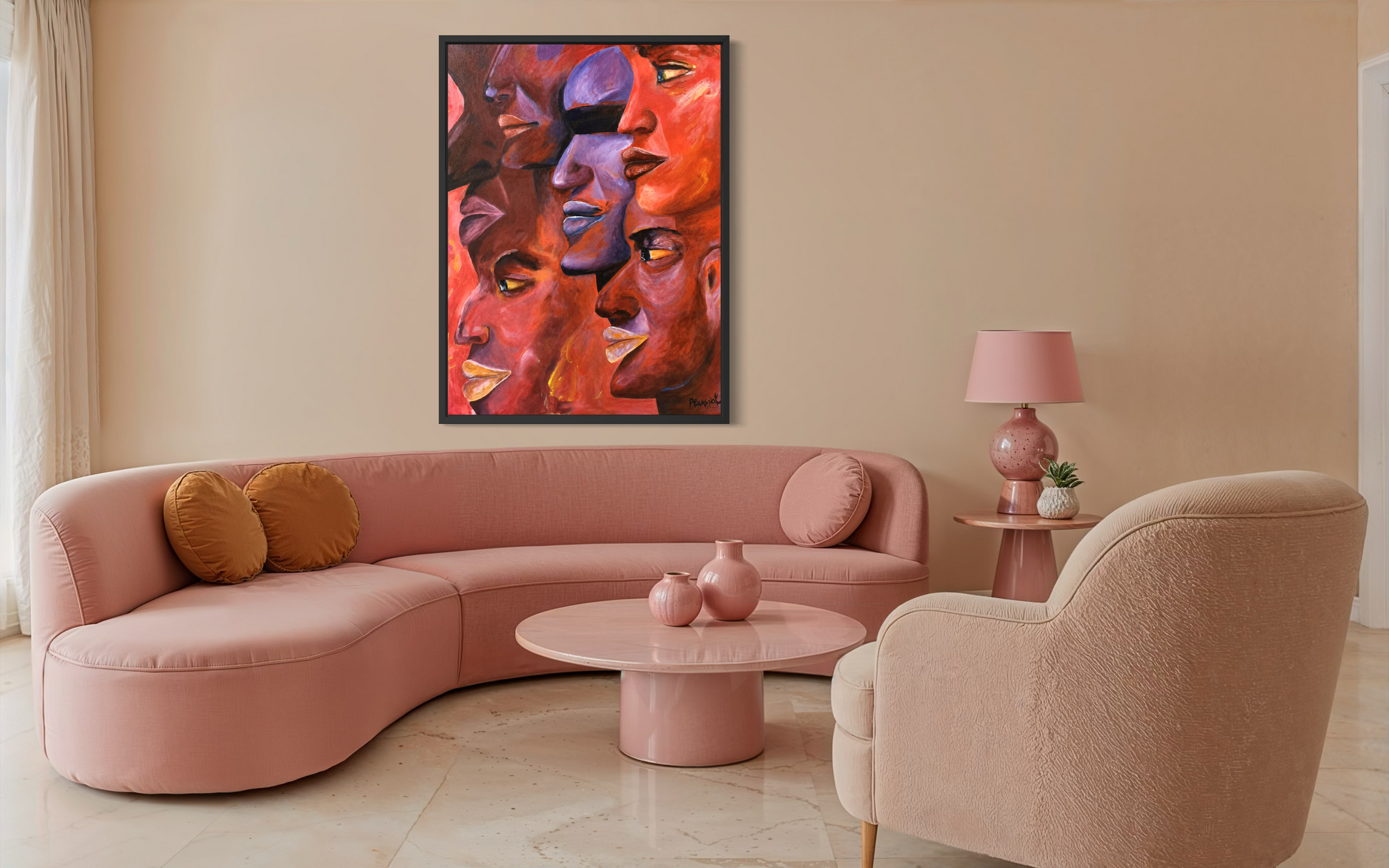 A framed abstract wall art print featuring multiple stylized faces in warm red, orange, pink, and purple tones, displayed above a curved blush pink sectional sofa in a modern living room setting.