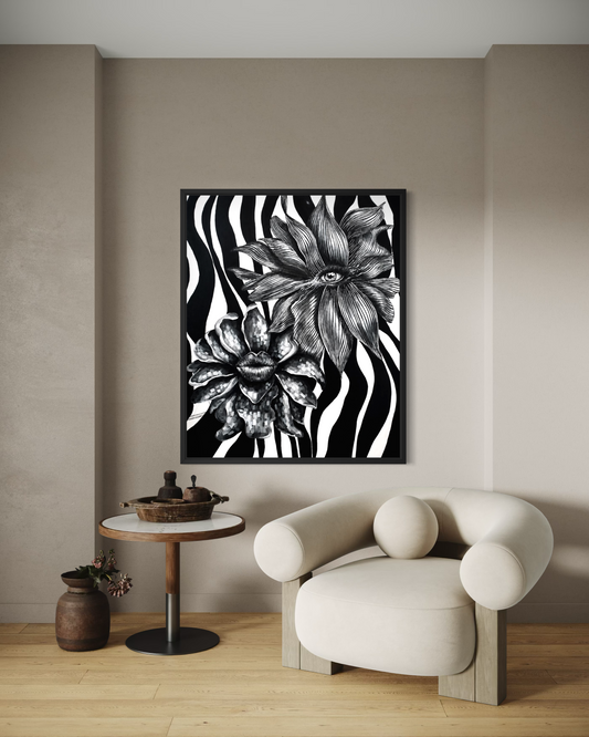 A framed black and white floral art print with zebra-like stripes hangs on a beige wall above a cream-colored modern armchair and a small round side table in a minimalist room setting.