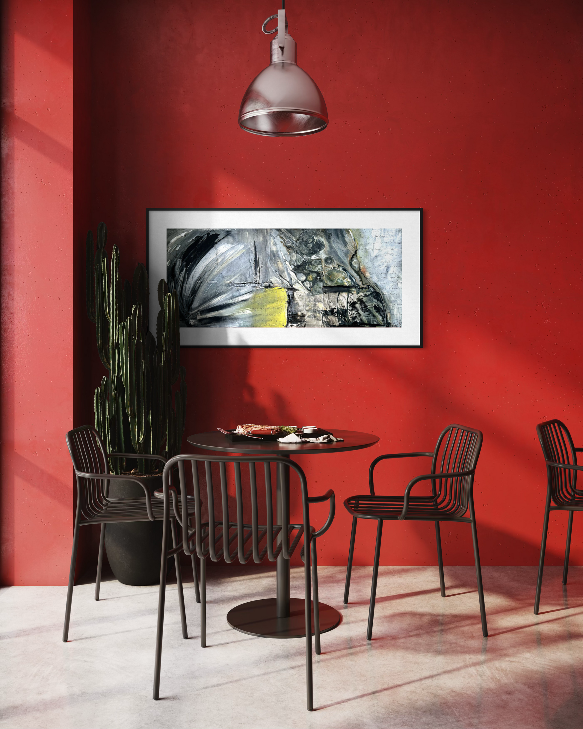 A framed abstract art print with black, gray, white, and yellow tones hangs on a bold red wall in a modern dining room setting with black metal chairs and a round table.