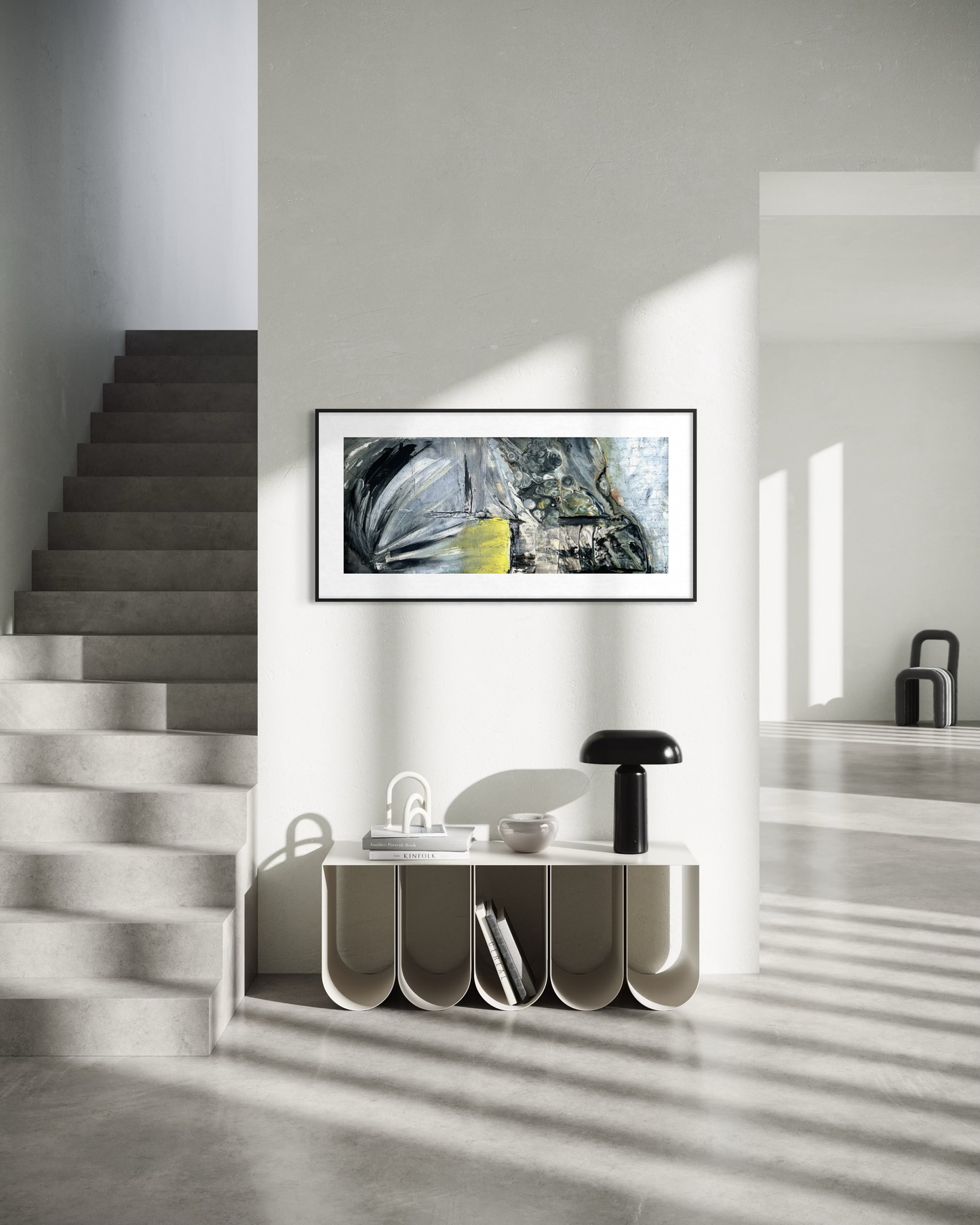 A framed abstract landscape art print with a yellow boat detail hangs on a white wall in a modern minimalist interior with concrete stairs and floor shadows.