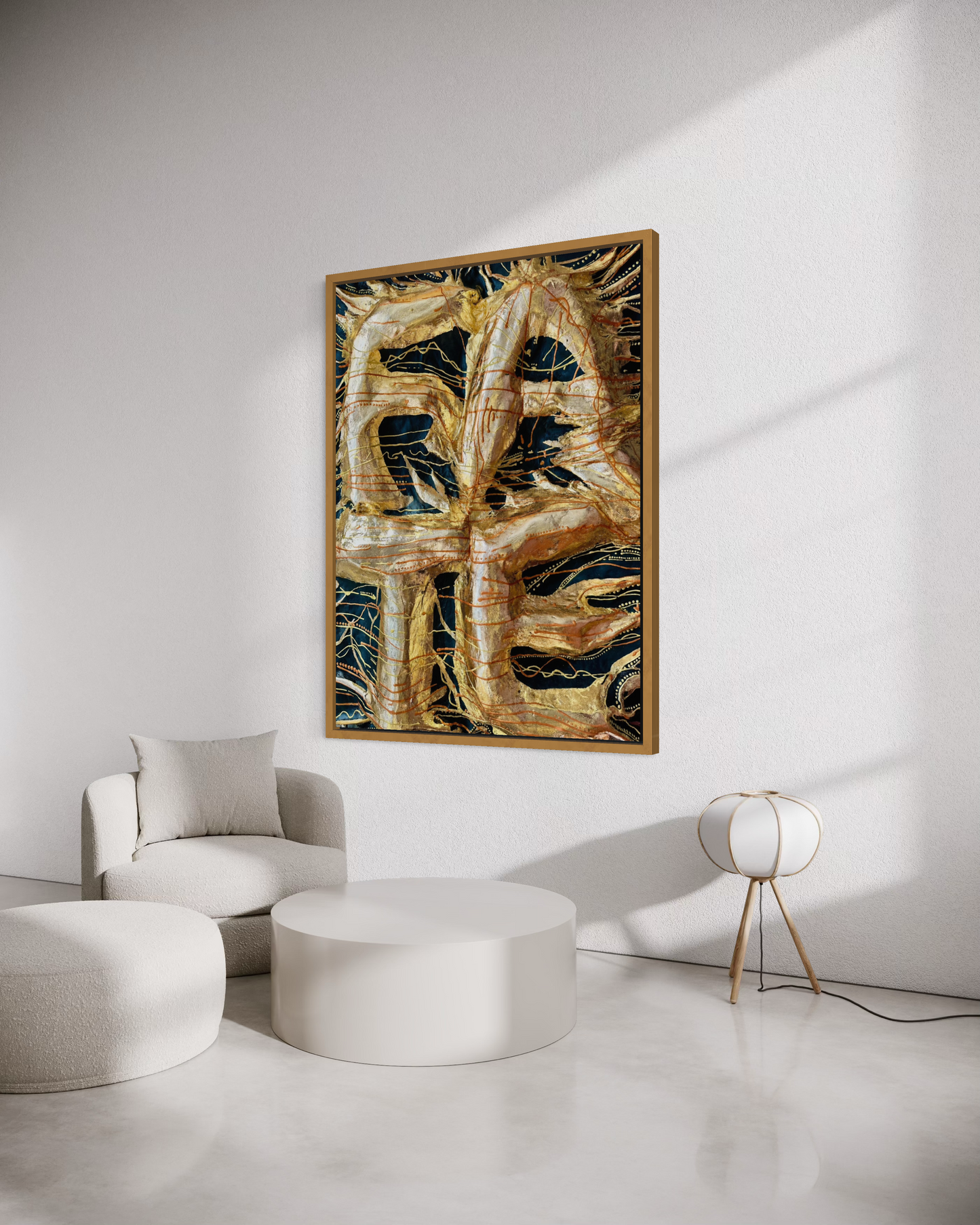 A framed abstract painting featuring textured gold and black brushstrokes, displayed on a white wall in a modern minimalist living room setting with a white armchair, round ottomans, and a small table lamp.