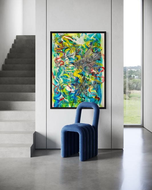 A framed abstract art print featuring vibrant green, blue, yellow, and red brushstrokes, displayed on a white wall in a modern interior setting with a blue ribbed chair in the foreground.