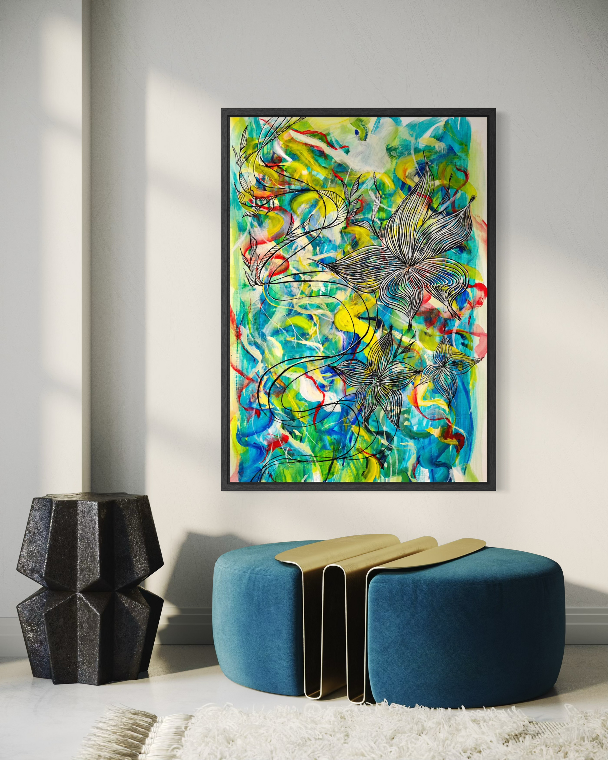 A framed abstract painting with vibrant green, blue, yellow, and red brushstrokes hangs on a light gray wall above a teal velvet ottoman in a modern styled room.